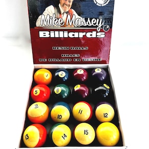 May include: A box set of resin billiard balls, featuring the text "Mike Massey Billiards". The balls are numbered 1 to 15, with a variety of colours including yellow, red, blue, and purple. The box also has text in French.