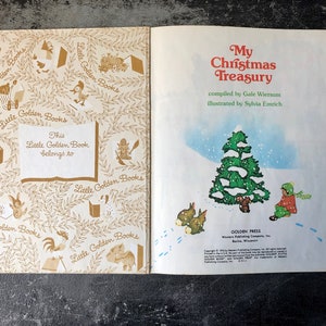 May include: A vintage Little Golden Book titled "My Christmas Treasury" compiled by Gale Wiersum and illustrated by Sylvia Emrich. The cover features a snowy scene with a green Christmas tree and a child in a red coat standing near it.