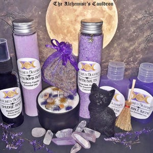 May include: A collection of Witches Slumber products including a black spray bottle, a tall tube of bath bomb dust, a tall tube of bath salts, a purple organza bag, a black candle, two purple bottles, and a black cat figurine with crystals.