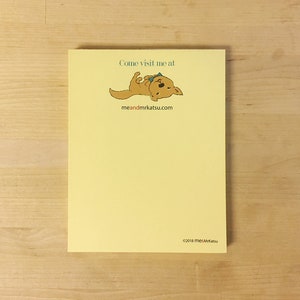 May include: Yellow notepad with a cartoon dog wearing a bow tie. The text on the notepad reads "Come visit me at meandmrkatsu.com". The copyright text at the bottom reads "©2018 me&MrKatsu".