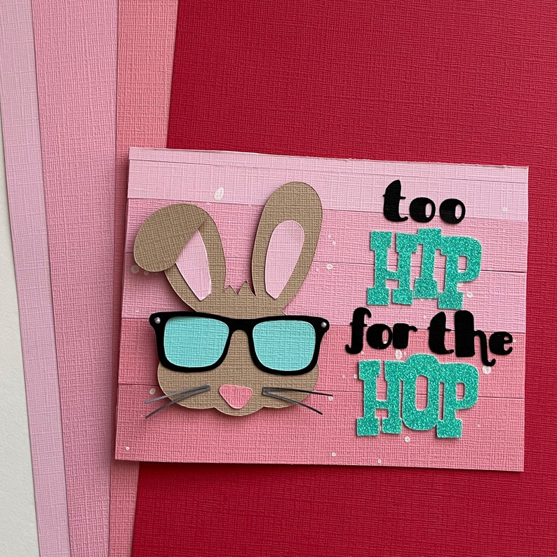 May include: A pink and brown card with a bunny wearing sunglasses and the text "too hip for the hop" in black and teal letters.