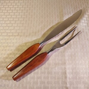 May include: A set of two kitchen utensils with wooden handles. The knife and fork are made of stainless steel and have a modern design.