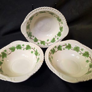 Könnte beinhalten: Drei weiße Keramik-Servierschalen mit einem grünen Efeublatt-Design am Rand. Die Schalen haben einen gewellten Rand und eine seilartige Bordüre. Die Schalen sind oval und haben Griffe auf beiden Seiten.