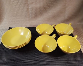 May include: Set of four yellow ceramic cups and a set of four yellow ceramic bowls. The cups have handles and the bowls are stacked.