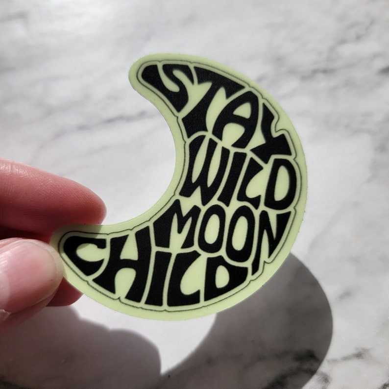 Pu&ograve; includere: Un adesivo che brilla al buio a forma di luna crescente con il testo "Stay Wild Moon Child" in nero.