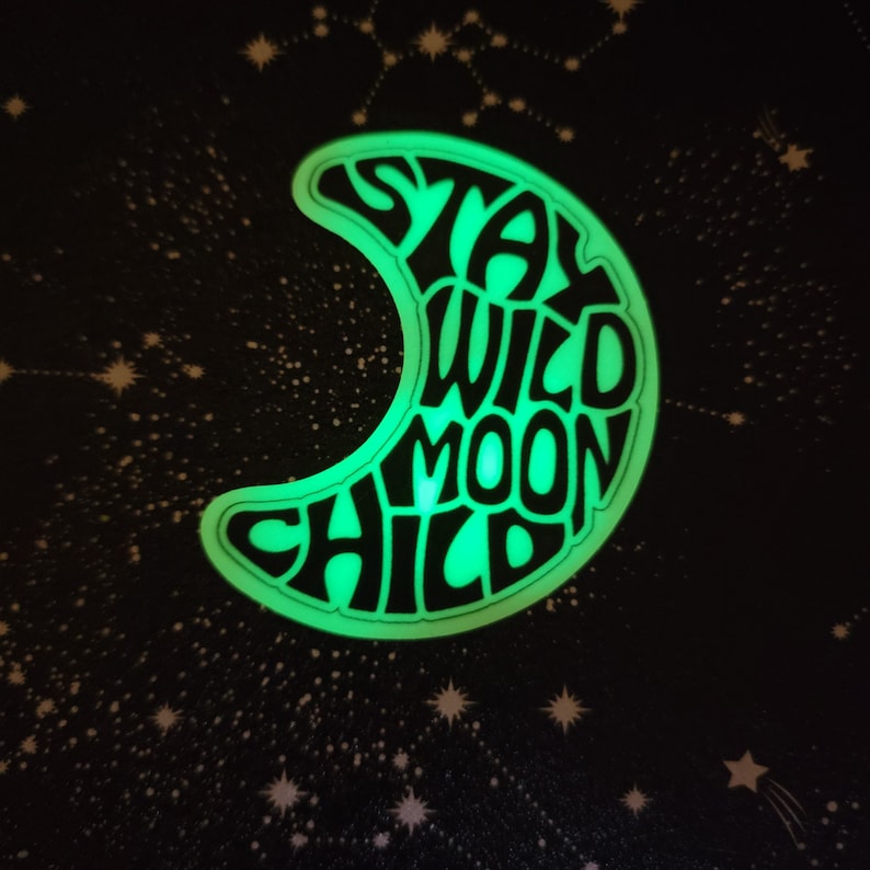 Pu&ograve; includere: Un adesivo che brilla al buio a forma di luna crescente con il testo "Stay Wild Moon Child" in un font retr&ograve;.