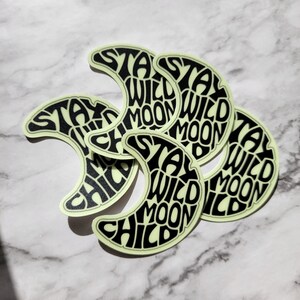 Pu&ograve; includere: Cinque adesivi a forma di luna crescente che brillano al buio con il testo "Stay Wild Moon Child" in nero.