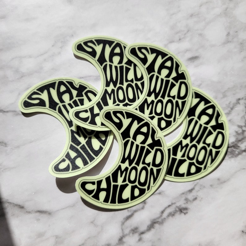Pu&ograve; includere: Cinque adesivi a forma di luna crescente che brillano al buio con il testo "Stay Wild Moon Child" in nero.