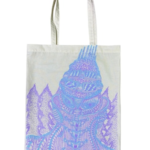 Puede incluir: Un bolso tote de color crema con una ilustración detallada de una figura con casco y patrones intrincados en tonos azules y morados. El diseño incluye una estructura similar a una montaña. El bolso tiene dos asas.