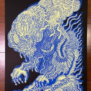 May include: A blue and yellow illustration of a creature with intricate patterns and details. The artwork features a black background and a unique, stylized design. The creature has a large head and a detailed body, with a textured appearance.