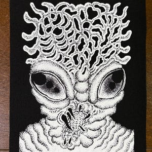 Könnte beinhalten: Schwarz-weißer Aufnäher mit einer detaillierten Illustration eines außerirdischen Wesens. Das Wesen hat große Augen und einen strukturierten Kopf. Das Design wird mit einer Punktiertechnik erstellt.