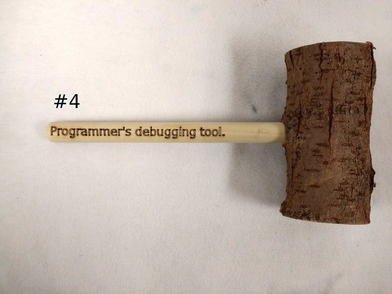 Pode incluir: Um martelo de madeira com acabamento em casca natural e uma al&ccedil;a que diz "Ferramenta de depura&ccedil;&atilde;o para programadores."