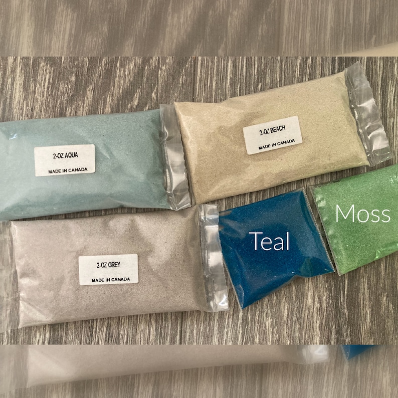 May include: Six small bags of colored sand, each labeled with the color and size. The colors are aqua, beach, grey, teal, moss, and grey. Each bag is labeled "2 oz" and "Made in Canada".