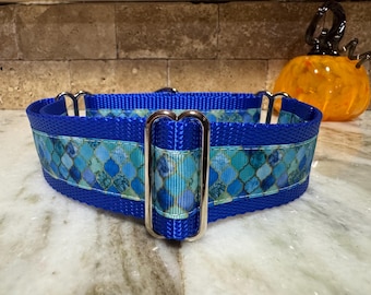 Könnte beinhalten: Ein blauer Hundehalsband mit einem dekorativen Band mit einem Mosaikmuster in Blau- und Türkistönen. Das Halsband hat silberfarbene Metallbeschläge. Im Hintergrund befindet sich ein dekorativer Glaskürbis.