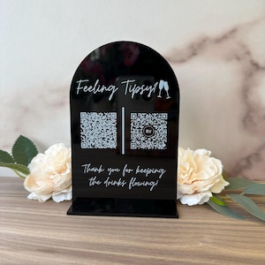 May include: Black acrylic sign with a rounded top, featuring the text "Feeling Tipsy!" and two champagne glasses. The sign also includes two QR codes and the text "Thank you for keeping the drinks flowing!"