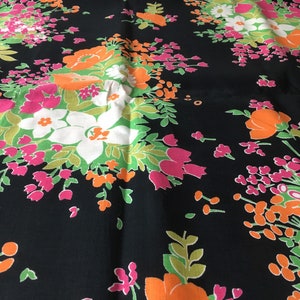 May include: Black fabric with a floral pattern in shades of pink, orange, green, and white. The flowers are stylized and have a retro look.