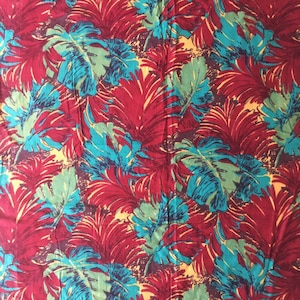 May include: A red fabric with a tropical leaf pattern in shades of teal, green, and yellow.