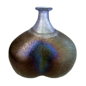May include: A decorative glass vase with a bulbous body and a slender neck. The vase has a textured, iridescent surface with a blend of brown, blue, and purple hues. The top of the vase is a light blue colour.