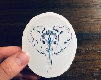 May include: A white oval sticker with a blue and black line drawing of an elephant's head with intricate designs. The text "brilliantly" is written on the sticker.