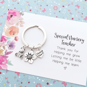 May include: A silver keyring with a teddy bear, flower, and heart charm. The card reads "Special Nursery Teacher" and includes the text "Thank you for Helping me grow Letting me be little Helping me learn".