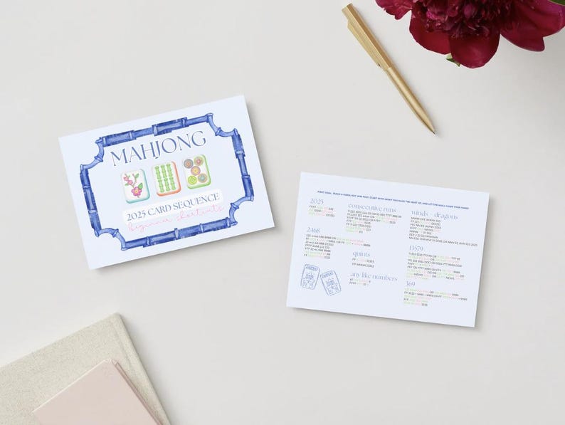 May include: Two white cards with text and illustrations on a light background. One card features "MAHJONG" in blue, with illustrations of tiles and "2025 CARD SEQUENCE". The other card has text and illustrations. A gold pen and a red flower are also present.