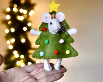 Puede incluir: Adorno navideño hecho a mano con un ratón blanco disfrazado de árbol de Navidad verde. El árbol tiene adornos redondos de colores y una estrella amarilla en la parte superior. El ratón tiene orejas rosas y una larga cola rosa.