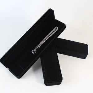 May include: A black velvet jewellery box with a silver necklace and a blue gemstone pendant inside.