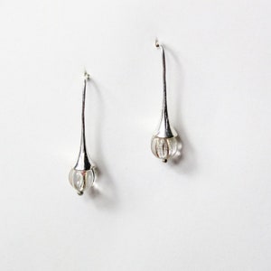 May include: A pair of silver drop earrings with clear glass teardrop-shaped beads.