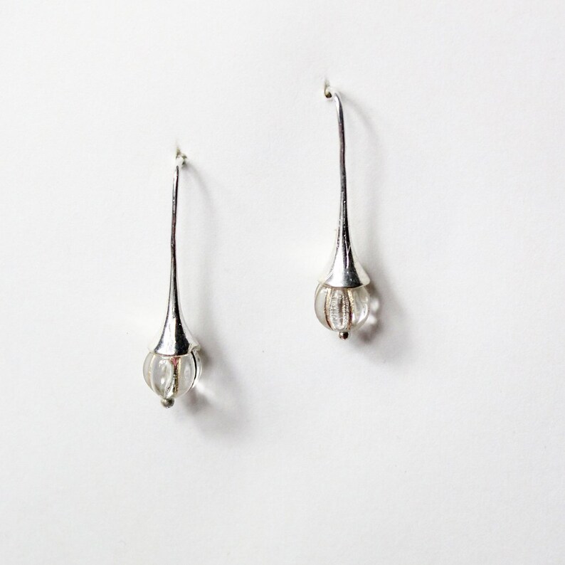 May include: A pair of silver drop earrings with clear glass teardrop-shaped beads.