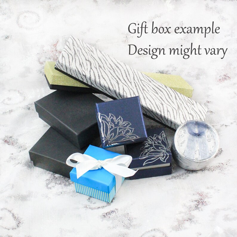 May include: Assortment of gift boxes in various colors and patterns. The boxes are made of cardboard and have a variety of designs, including floral patterns, stripes, and a zebra print. The text "Gift box example Design might vary" is visible in the image.