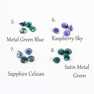 May include: Assortment of glass beads in various colors, including green, blue, and purple. The beads are arranged in groups of four, with each group labeled with a number and a descriptive name. The names include "Metal Green Blue", "Raspberry Sky", "Sapphire Celsian", and "Satin Metal Green".