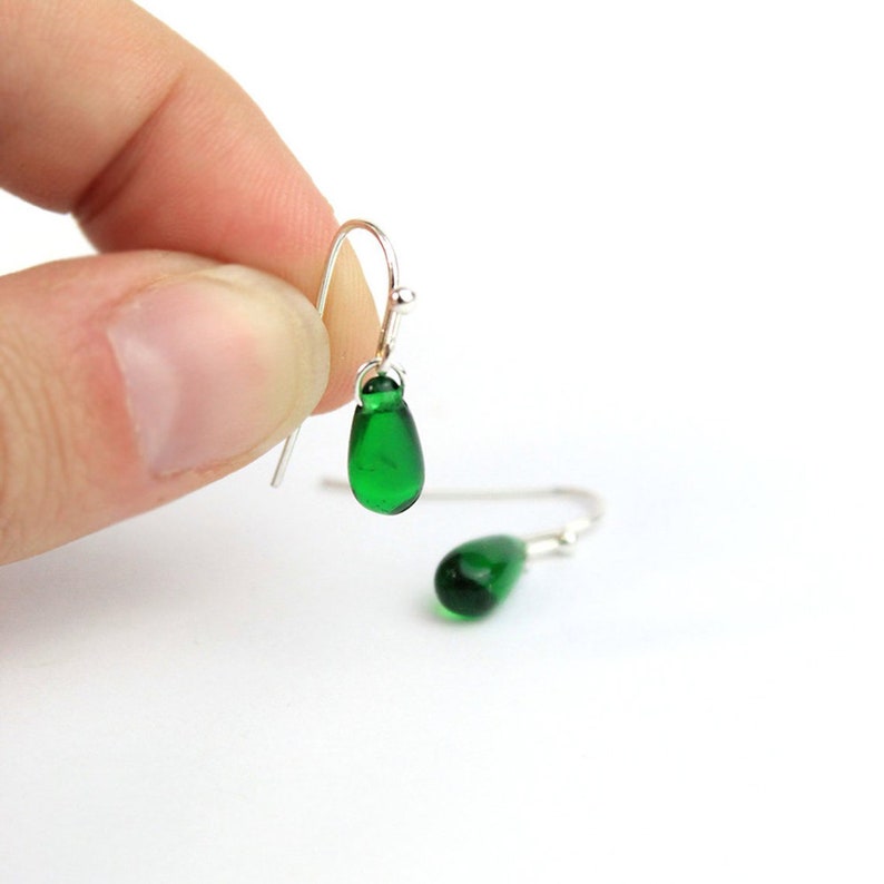 May include: A pair of silver dangle earrings with green glass teardrop-shaped beads.