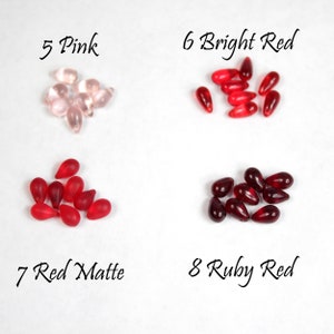 May include: Assortment of glass teardrop beads in various shades of red and pink.  The beads are labeled with numbers and color names: 5 Pink, 6 Bright Red, 7 Red Matte, 8 Ruby Red.