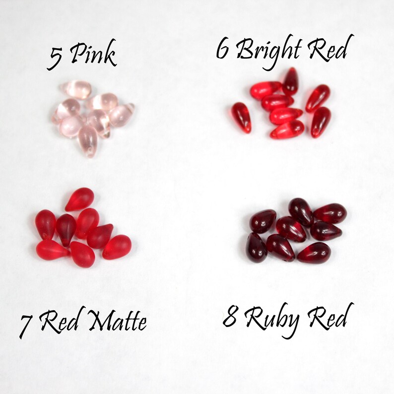 May include: Assortment of glass teardrop beads in various shades of red and pink.  The beads are labeled with numbers and color names: 5 Pink, 6 Bright Red, 7 Red Matte, 8 Ruby Red.