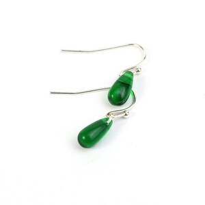 May include: A pair of silver dangle earrings with green teardrop-shaped glass beads.