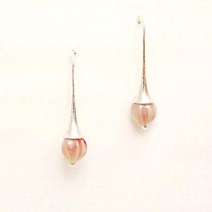 May include: A pair of silver dangle earrings with pink and white striped glass beads at the end of each earring.