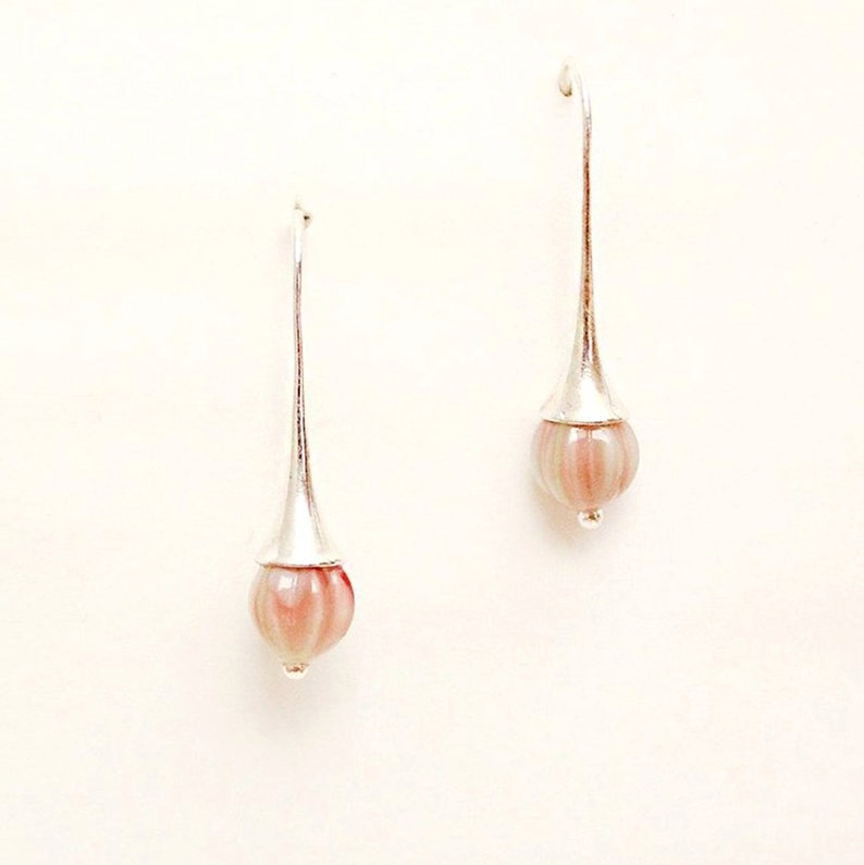 May include: A pair of silver dangle earrings with pink and white striped glass beads at the end of each earring.