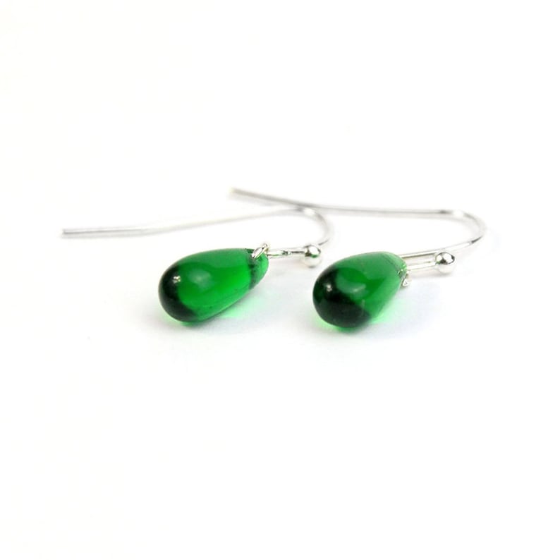May include: A pair of silver dangle earrings with green glass teardrop shaped beads.