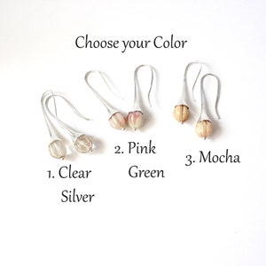 May include: Three pairs of earrings with different colored glass beads. The earrings are silver and have a teardrop shape. The beads are clear, pink, and mocha.