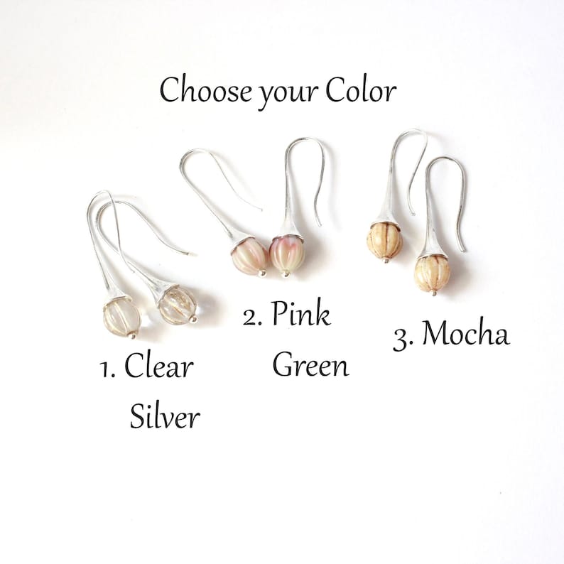 May include: Three pairs of earrings with different colored glass beads. The earrings are silver and have a teardrop shape. The beads are clear, pink, and mocha.
