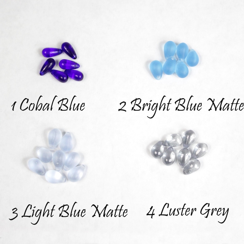 May include: Four piles of glass beads in different colors and finishes.  1 Cobal Blue, 2 Bright Blue Matte, 3 Light Blue Matte, 4 Luster Grey.