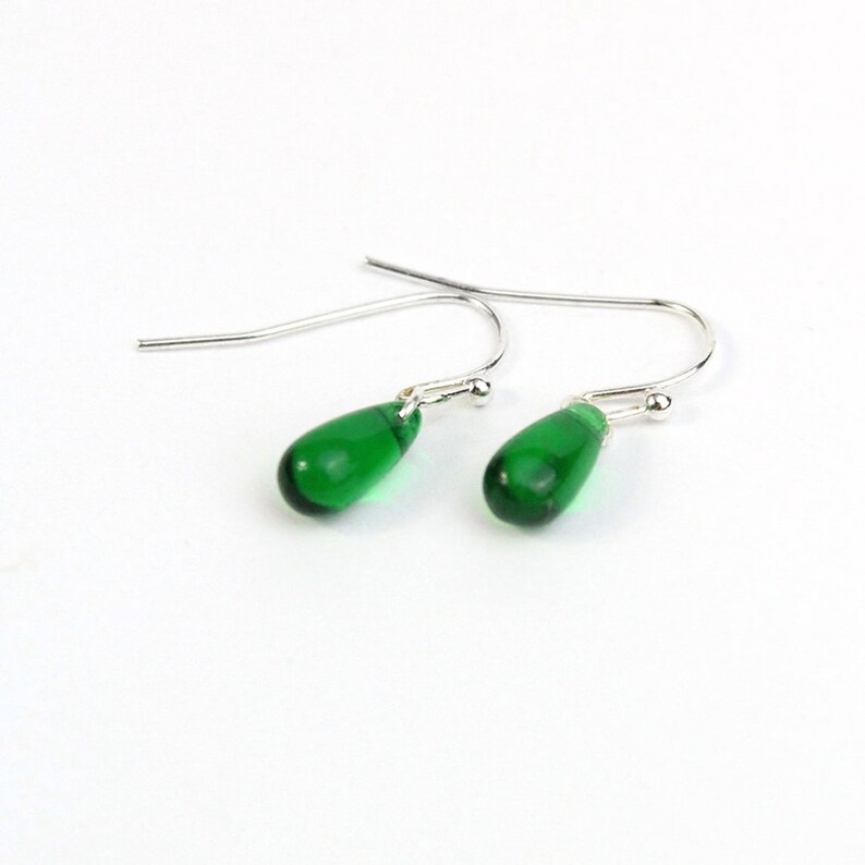 May include: A pair of silver dangle earrings with teardrop-shaped green glass beads.
