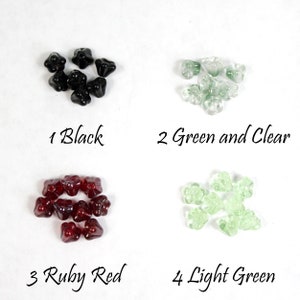 May include: Four groups of flower-shaped beads in black, green and clear, ruby red, and light green. The image includes the text "1 Black", "2 Green and Clear", "3 Ruby Red", and "4 Light Green".