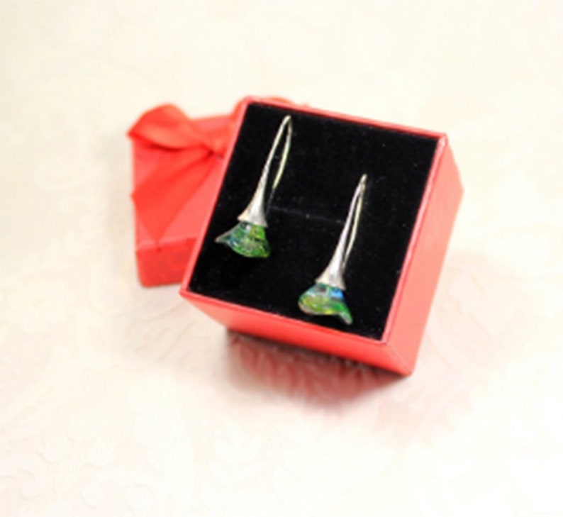 May include: A pair of silver earrings with green and blue iridescent glass flowers in a red gift box.