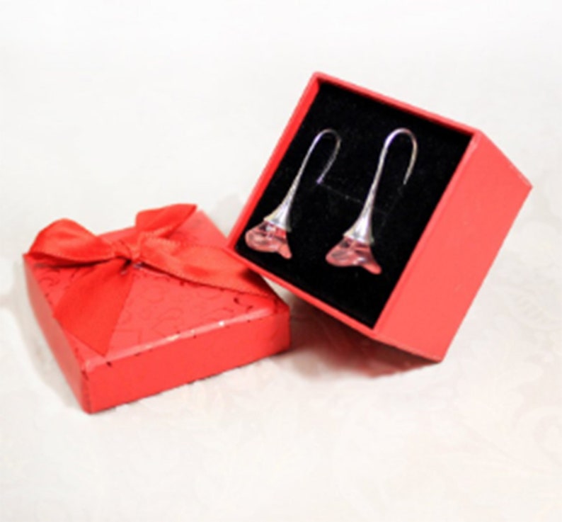 May include: A pair of pink crystal flower earrings in a red gift box with a red ribbon.