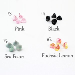 May include: Four different colors of glass flower beads. The beads are in the shape of a flower with five petals. The colors are pink, black, sea foam green, and fuchsia and lemon.