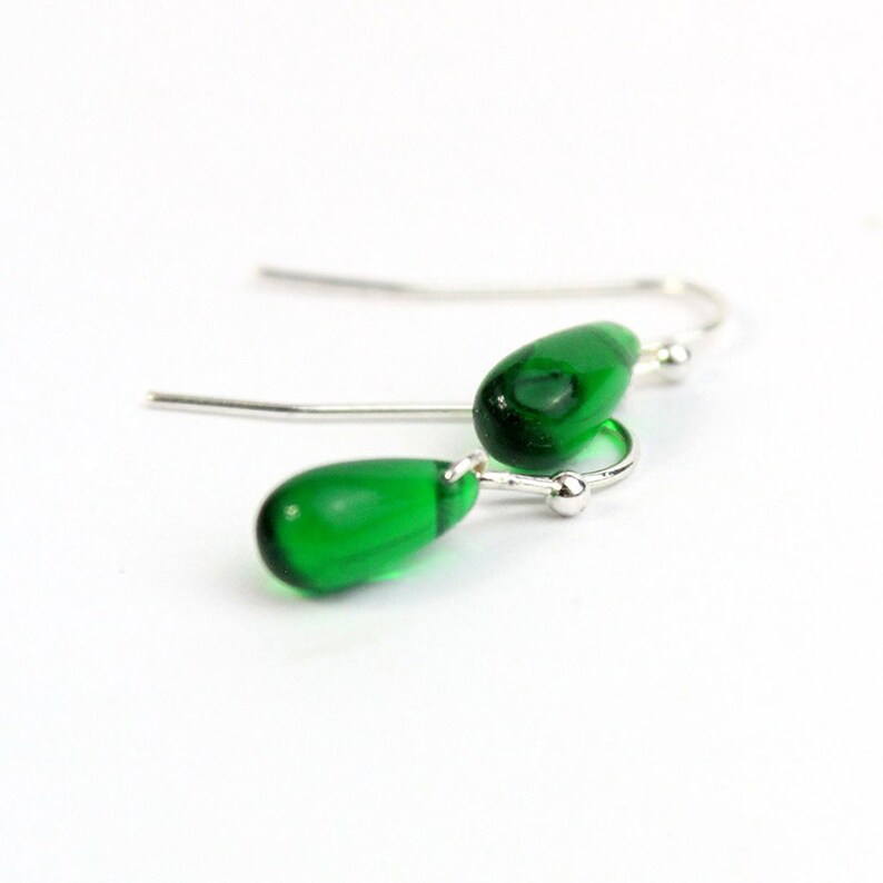 May include: A pair of silver dangle earrings with green teardrop-shaped glass beads.