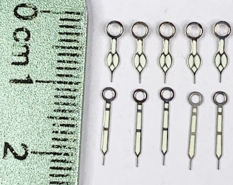 Puede incluir: Un conjunto de diez agujas de reloj, incluyendo agujas de hora, minuto y segundo. Las agujas están hechas de metal y tienen un revestimiento luminiscente blanco. Las agujas miden aproximadamente 1 cm de largo.