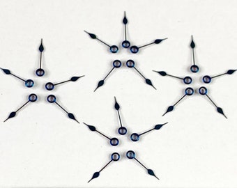 Könnte beinhalten: Drei Sätze blauer Uhrzeiger in Sternform. Die Zeiger sind 2,5 cm lang und haben jeweils ein kleines Loch in der Mitte. Die Zeiger sind in einem dreieckigen Muster auf einer weißen Oberfläche angeordnet.