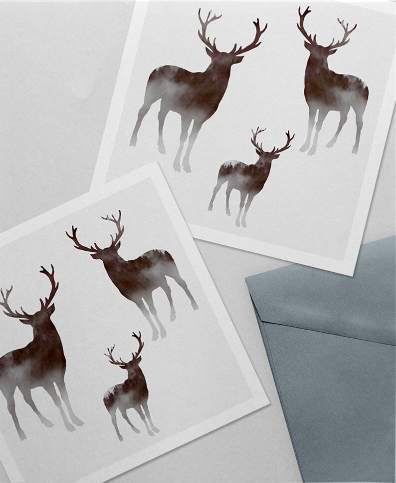 Puede incluir: Dos tarjetas blancas con una silueta marr&oacute;n de un ciervo con un bosque en su interior. Los ciervos son de diferentes tama&ntilde;os. Las tarjetas est&aacute;n sobre una superficie gris con un sobre gris.